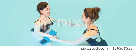 Two adult caucasian women practicing aqua therapy in pool for relaxation 136568532