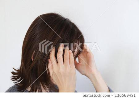 Woman holding her temples, headache, stress Woman holding her temples, headache, stress 136569451