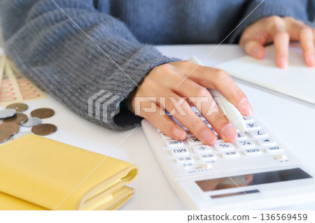 Woman's hands doing calculations Saving and living expense management 136569459