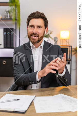 Middle-aged businessman consultant presents on camera smiles and speaks during video conference live Middle-aged businessman consultant presents on camera smiles and speaks during video conference live 136572650