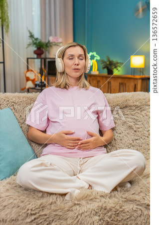 Pregnant woman meditation headphones ocean waves sound calm posture hands on belly focus balance zen Pregnant woman meditation headphones ocean waves sound calm posture hands on belly focus balance zen 136572659