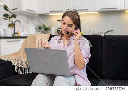 Young woman with headset starts laptop video call with client greets listens asks helpful questions 136572704