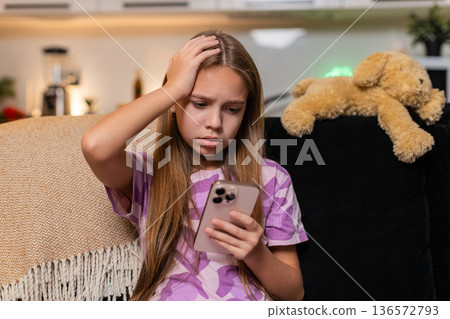 Teenager girl sees defeat alert on smartphone disappointed reaction sigh frown looks down quiet mood 136572793