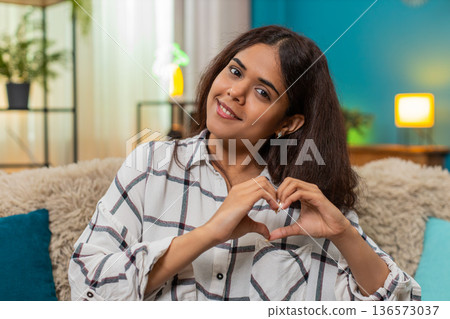 Indian woman forms heart hands blowing kiss toward camera expressing love affection joyful greeting Indian woman forms heart hands blowing kiss toward camera expressing love affection joyful greeting 136573037