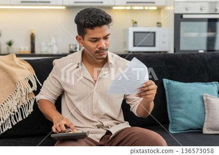 Indian man plans utility budget uses calculator holds bills squints and marks priorities for month Indian man plans utility budget uses calculator holds bills squints and marks priorities for month 136573058
