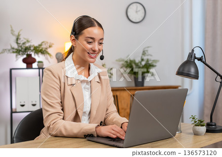 Young businesswoman with headset answers support call greets caller asks questions and stays polite 136573120
