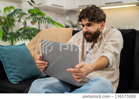 Indian man laptop worker reading job rejection email tired sighs holds head feeling stress and worry Indian man laptop worker reading job rejection email tired sighs holds head feeling stress and worry 136573888