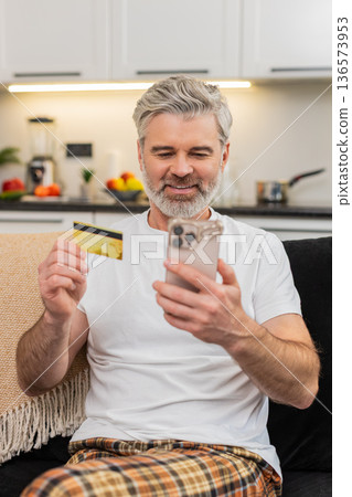 Middle-aged man confirms payment on smartphone checks order amount sees receipt feels satisfied Middle-aged man confirms payment on smartphone checks order amount sees receipt feels satisfied 136573953