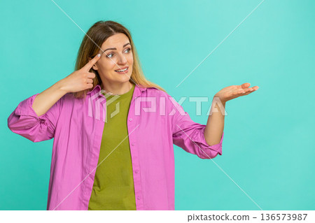 Woman spinning finger near temple showing crazy gesture disbelief or joking insult to silly behavior 136573987