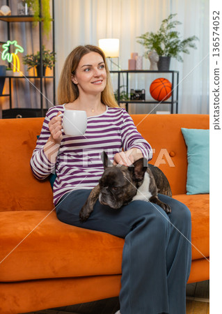 Middle-aged woman with dog enjoys morning tea relaxes calm mood simple break warm drink quiet moment Middle-aged woman with dog enjoys morning tea relaxes calm mood simple break warm drink quiet moment 136574052