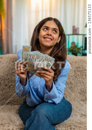 Indian woman counting cash dollars with satisfied smile, feeling financial success and wealth Indian woman counting cash dollars with satisfied smile, feeling financial success and wealth 136575133