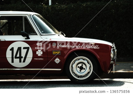 A classic car in sunlight filtering through the trees, a racing version of the Alfa Romeo Giulia Super A classic car in sunlight filtering through the trees, a racing version of the Alfa Romeo Giulia Super 136575856