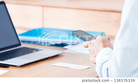 A man preparing his tax return using a computer and smartphone A man preparing his tax return using a computer and smartphone 136576339