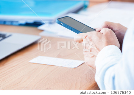 A man preparing his tax return using a computer and smartphone A man preparing his tax return using a computer and smartphone 136576340