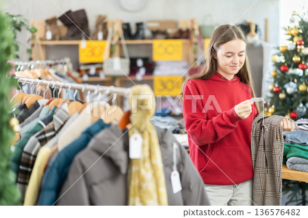 Teenage girl choosing trousers in clothing store Teenage girl choosing trousers in clothing store 136576482