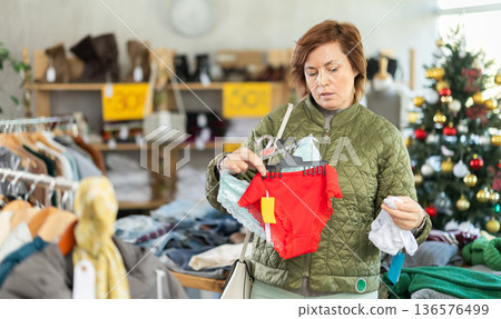 Woman picks up clothes and chooses panties, New Year Eve sale Woman picks up clothes and chooses panties, New Year Eve sale 136576499