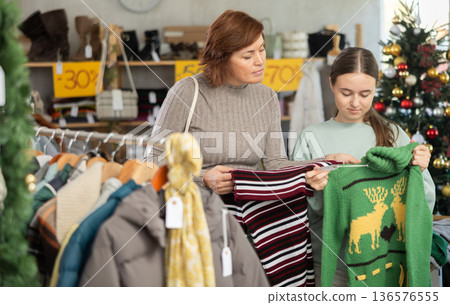 Mother with her teenage daughter choose sweater together in fashionable clothing store Mother with her teenage daughter choose sweater together in fashionable clothing store 136576555