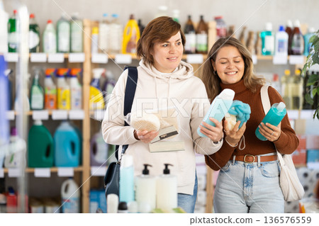 Two women holding shower gel choosing body washcloth in department store Two women holding shower gel choosing body washcloth in department store 136576559