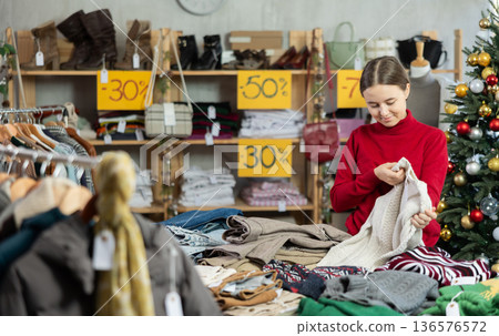 Teenage girl chooses a sweater in fashion boutique. Teenage girl chooses a sweater in fashion boutique. 136576572