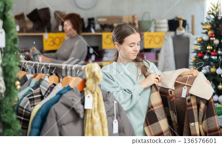 In sales area of store during Christmas sale, teen girl customer choose plaid jacket In sales area of store during Christmas sale, teen girl customer choose plaid jacket 136576601