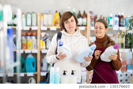 Young saleswoman offering detergent to female customer Young saleswoman offering detergent to female customer 136576603