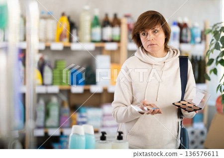 Store visitor woman purchases in household chemicals department, choose eye shadow pallet Store visitor woman purchases in household chemicals department, choose eye shadow pallet 136576611
