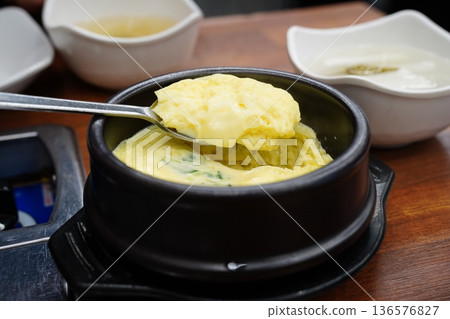 Fluffy Korean steamed egg, Gyeran-jjim, served in a hot stone pot on wooden table 136576827