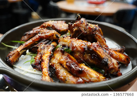 Delicious Korean BBQ grilled pork ribs, Jjokgalbi, with sesame seeds and green onions on a black plate Delicious Korean BBQ grilled pork ribs, Jjokgalbi, with sesame seeds and green onions on a black plate 136577668