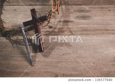 Wooden cross, crown of thorns and three iron nails on rustic wooden table, warm dramatic light and copy space, symbolizing crucifixion, sacrifice, Holy Week, Good Friday and Easter. Wooden cross, crown of thorns and three iron nails on rustic wooden table, warm dramatic light and copy space, symbolizing crucifixion, sacrifice, Holy Week, Good Friday and Easter. 136577680