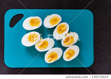 Boiled and raw eggs arranged on a green cutting board, sliced halves served with mayonnaise. Homemade breakfast or cooking preparation concept. Boiled and raw eggs arranged on a green cutting board, sliced halves served with mayonnaise. Homemade breakfast or cooking preparation concept. 136578024