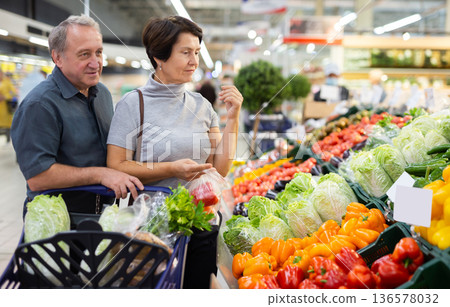 Mature woman and man selecting vegetables in greengrocer Mature woman and man selecting vegetables in greengrocer 136578032