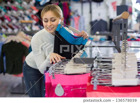 Young woman choosing sports pants in clothing store 136578039