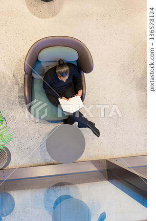Woman sitting and reading a book Woman sitting and reading a book 136578124