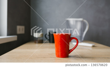 Red coffee mug on wooden table in minimalist kitchen setting 136578620