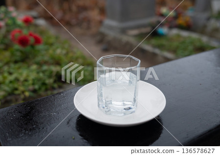 Glass of water on a white plate in a cemetery setting Glass of water on a white plate in a cemetery setting 136578627