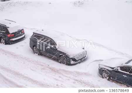 Cars buried in heavy snow on urban street during winter blizzard 136578649