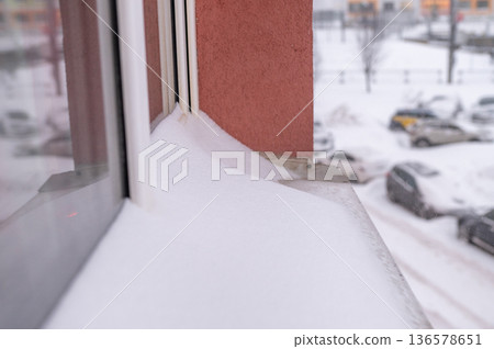 Snow accumulation on window sill from winter storm in urban setting 136578651