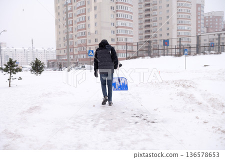 Male in winter attire shoveling snow in urban residential area Male in winter attire shoveling snow in urban residential area 136578653