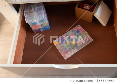 Organized craft drawer with beads and colored bands in plastic containers Organized craft drawer with beads and colored bands in plastic containers 136578668