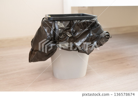 Empty trash bin with black plastic liner on wooden floor Empty trash bin with black plastic liner on wooden floor 136578674