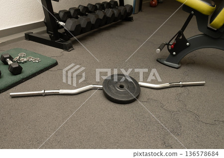 Empty gym with barbell and dumbbells on carpeted floor in fitness center 136578684