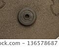 Single black weight plate on rough textured surface 136578687