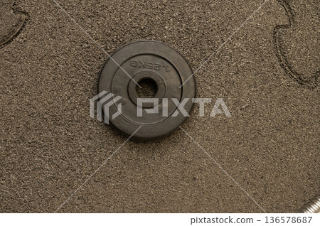 Single black weight plate on rough textured surface 136578687