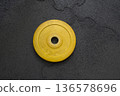 Yellow weight plate on gym floor for strength training and fitness 136578696