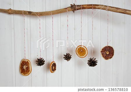 Simple Elegant DIY Christmas Decorations in Scandinavian Style. Minimal Christmas Natural Garland. Aesthetic Xmas Craft. Trendy Farmhouse Decor Idea. Dried Orange Slices, Cones Hanging on a Branch Simple Elegant DIY Christmas Decorations in Scandinavian Style. Minimal Christmas Natural Garland. Aesthetic Xmas Craft. Trendy Farmhouse Decor Idea. Dried Orange Slices, Cones Hanging on a Branch 136578810