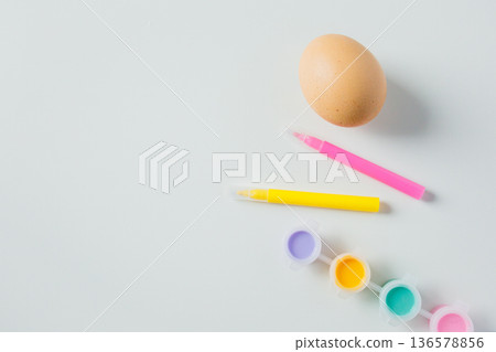 One Easter egg with bright colorful paints and markers on white background with copy space. Eggs decoration before Easter holidays One Easter egg with bright colorful paints and markers on white background with copy space. Eggs decoration before Easter holidays 136578856