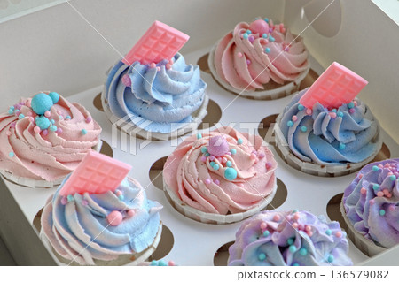 Colorful cupcakes with frosting and sprinkles perfect for festive celebration. Freshly baked cupcake box with creamy purple frosting. Decorated cakes. Sweet Dessert Preparation. Pastry small business 136579082