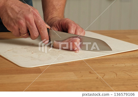 Man butcher cut raw meat with sharp knife at home kitchen. Male person cutting the chicken fillet pieces for cooking. Preparing chopping food. Split poultry breast. Healthy lean meat, low cholesterol 136579106