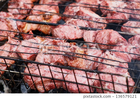 Pork Butt sliced on BBQ. Shish kebab. Pieces of pork on the grid, grilled meat with smoke. Food preparation process. Marinated spiced fillet meat cooked on charcoal barbeque grill. Outdoors cooking. Pork Butt sliced on BBQ. Shish kebab. Pieces of pork on the grid, grilled meat with smoke. Food preparation process. Marinated spiced fillet meat cooked on charcoal barbeque grill. Outdoors cooking. 136579121