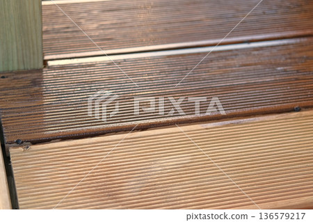 Brown oil for protection of wood by staining. Painting a larch for protecting and pests. Woodworker applying finish to terrace deck board. Repairman varnishing with brush wooden plank floor surface. 136579217